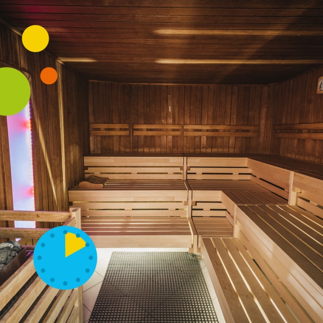 Innenaufnahme der Sauna im Triamare mit warmem Holzinterieur, mehreren Sitz- und Liegebänken sowie beleuchtetem Saunaofen im Vordergrund. Die gemütliche Atmosphäre und grafischen Elemente stehen für das ermäßigte 2-Stunden-Ticket für Erwachsene in der Sau