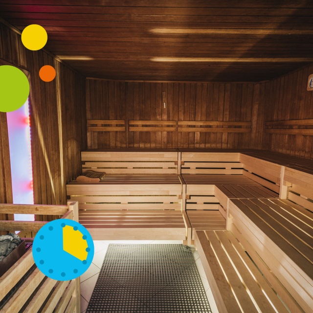 Innenaufnahme der Sauna im Triamare mit warmem Holzinterieur, mehreren Sitz- und Liegebänken sowie beleuchtetem Saunaofen im Vordergrund. Die gemütliche Atmosphäre und grafischen Elemente stehen für das ermäßigte 4-Stunden-Ticket für Erwachsene in der Sau
