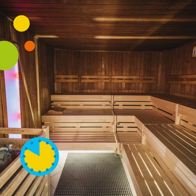 Innenaufnahme der Sauna im Triamare mit warmem Holzinterieur, großzügigen Sitz- und Liegebänken sowie beleuchtetem Saunaofen im Vordergrund. Die gemütliche Atmosphäre und grafischen Elemente stehen für die ermäßigte Tageskarte für Erwachsene in der Sauna.